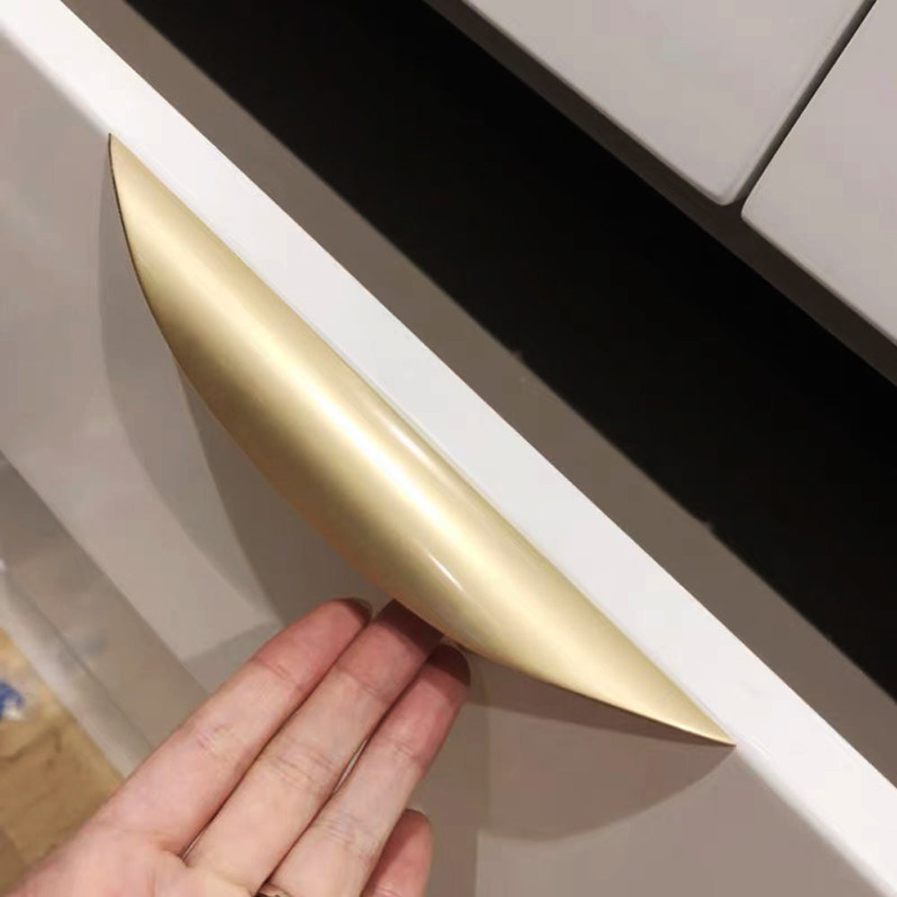 Brushed gold furniture handle with ergonomic curved design.