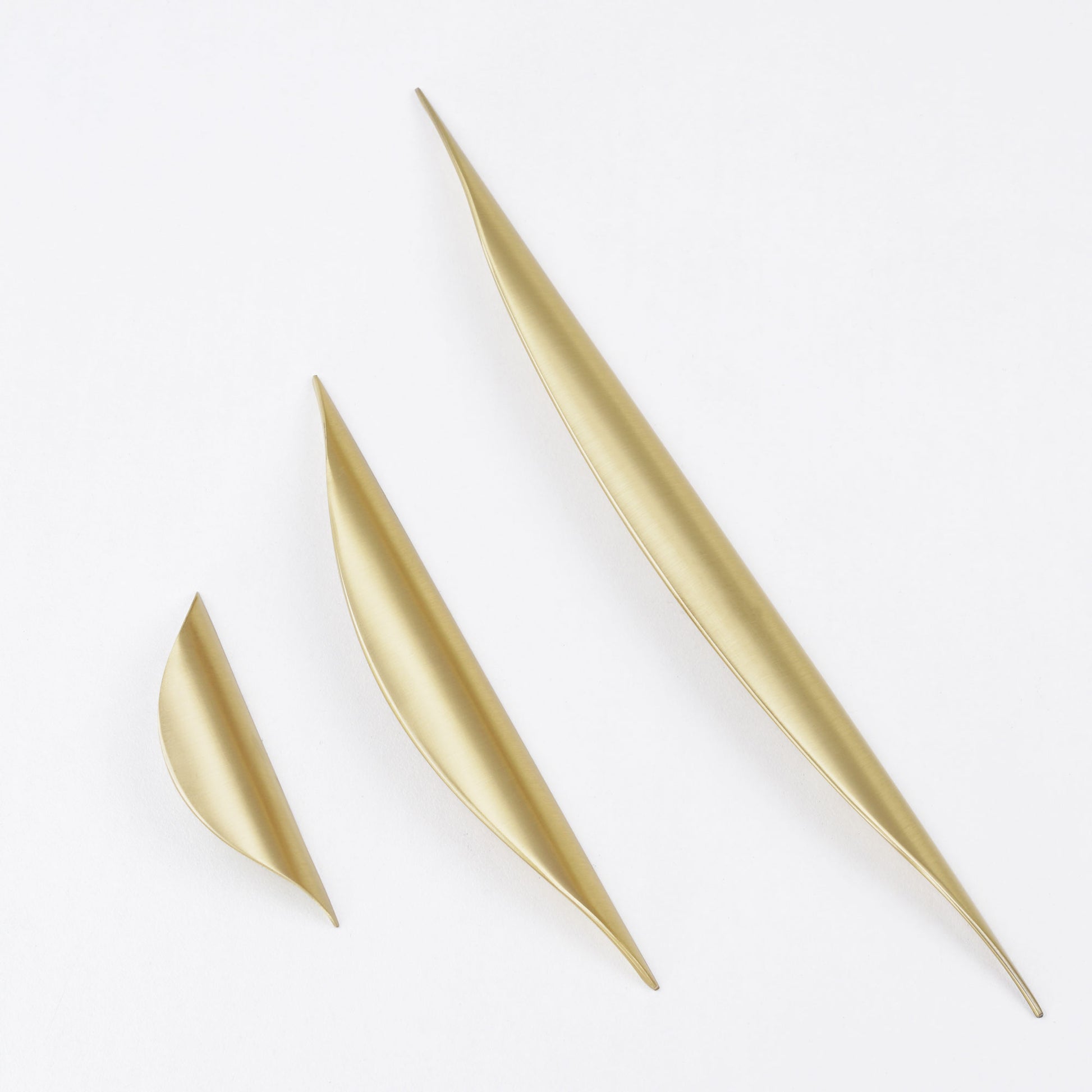 Contemporary brushed gold curved pull knob for furniture.