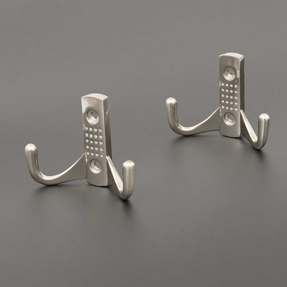 Four satin nickel hooks neatly aligned on a bedroom wall.